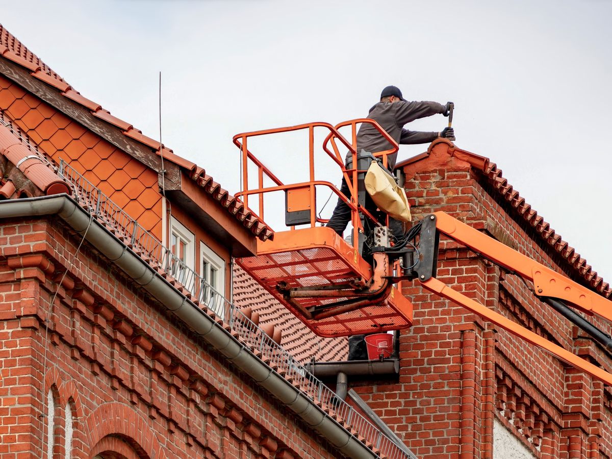Artisan couvreur effectuant un entretien de toiture en nacelle